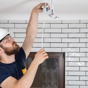 Elektriker montiert einen Deckenanschluss für eine Leuchte