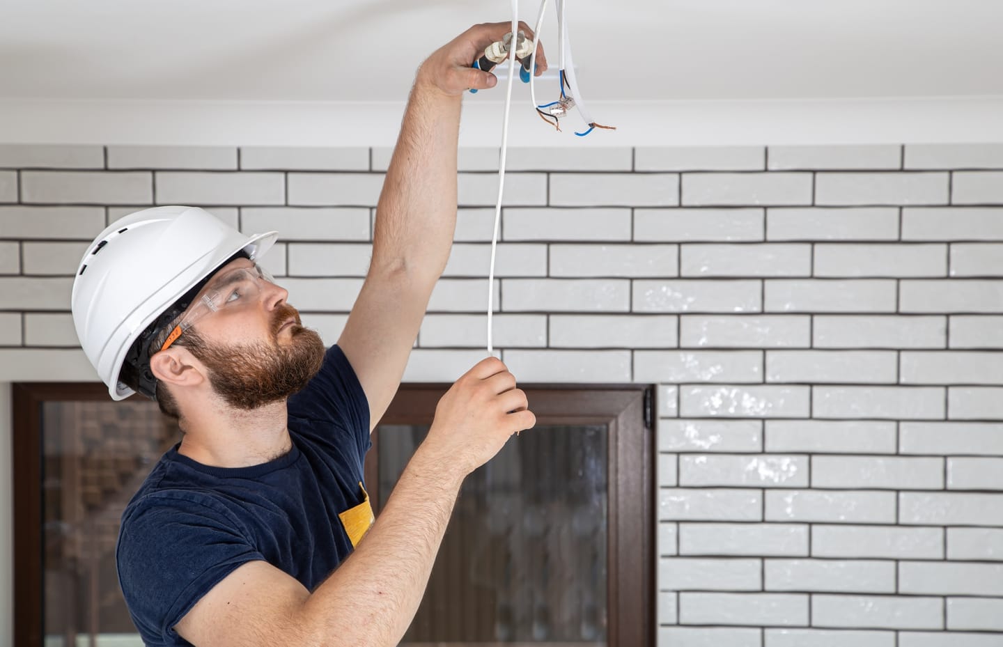 Elektriker montiert einen Deckenanschluss für eine Leuchte